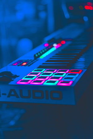 Neon-lit electronic music keyboard with glowing pads and keys in a dark studio setting HD phone wallpaper
