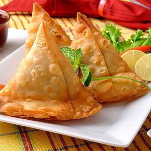 Golden Fried Samosas with Mint Garnish and Lemon Wedges on a White Plate HD phone wallpaper