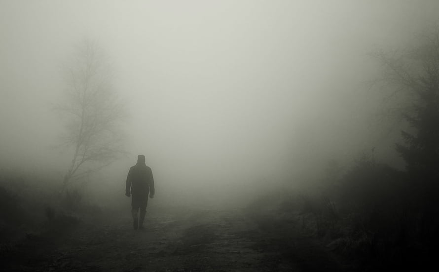 Solitary figure walking through dense fog on a desolate path HD wallpaper