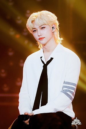 Felix from Stray Kids on stage in a white shirt and black tie with platinum blonde hair HD phone wallpaper
