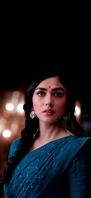 Mrunal Thakur in teal embroidered saree with ornate earrings and warm bokeh background HD phone wallpaper