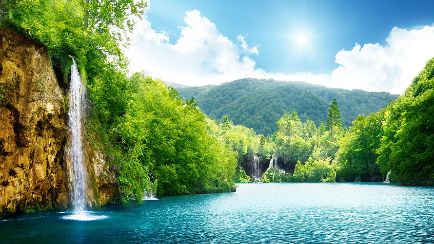 Serene Waterfall Cascading Into Turquoise Lake Surrounded By Lush Green Forest HD wallpaper