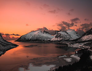 Snow-Capped Alpine Peaks Reflected in a Calm Lake Under a Vibrant Orange Sunset Sky HD wallpaper