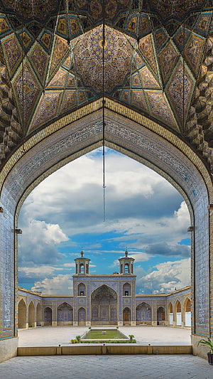 Ornate Islamic Archway Framing a Majestic Mosque Courtyard with Central Fountain HD phone wallpaper