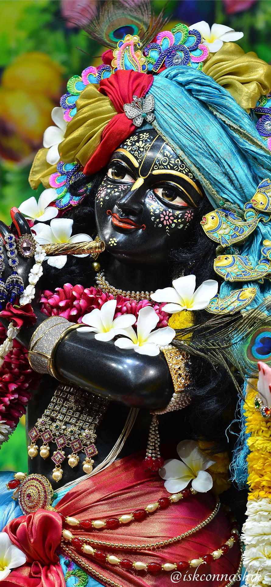 Ornate Krishna Murti Adorned With Peacock Feathers, Frangipani Flowers, And Traditional Jewelry HD phone wallpaper