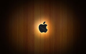 Illuminated Apple Logo on Warm Wood Grain Background HD wallpaper