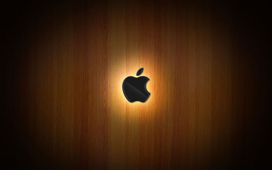 Illuminated Apple Logo on Warm Wood Grain Background HD wallpaper