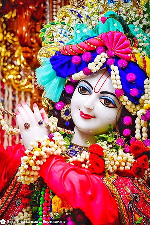 Ornate Krishna Murti Adorned With Vibrant Floral Garland And Traditional Temple Jewelry HD phone wallpaper