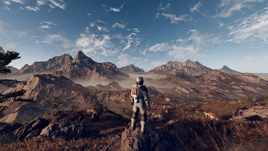 Starfield Astronaut Standing on Rocky Outcrop Overlooking Vast Mountain Range HD wallpaper