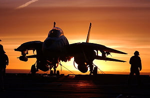 F-14 Tomcat fighter jet silhouette on an aircraft carrier deck at sunset HD wallpaper
