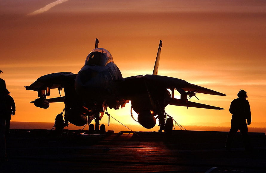 F-14 Tomcat fighter jet silhouette on an aircraft carrier deck at sunset HD wallpaper