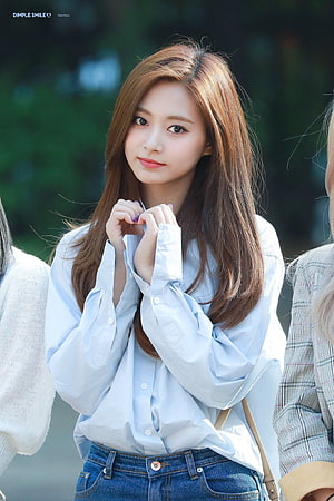 Tzuyu in a light blue button-down shirt and denim jeans with a soft outdoor background HD phone wallpaper
