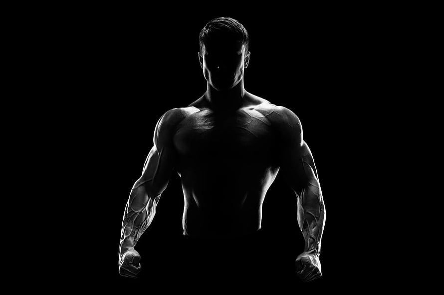 Dramatic Silhouette of a Muscular Male Athlete in a Dark Gym Setting HD wallpaper