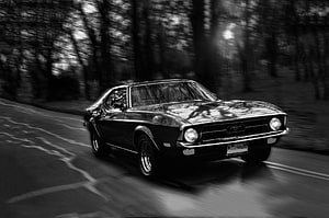 Classic Black Ford Mustang Cruising Through a Forest Road in Monochrome HD wallpaper