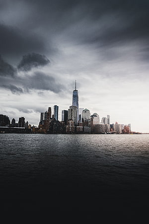 New York City Lower Manhattan Skyline Viewed Across The Water Under Dramatic Storm Clouds HD phone wallpaper