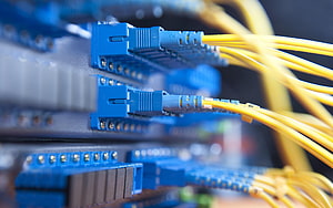 Close-up of blue network patch panel with yellow fiber optic cables connected to SC connectors HD wallpaper