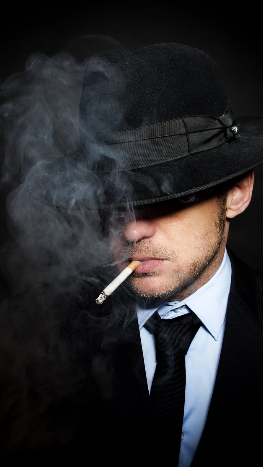 Man in Black Fedora Smoking Cigarette with Dramatic Smoke Against Dark Background HD phone wallpaper