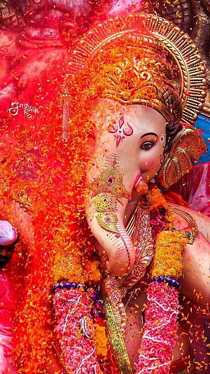 Lord Ganesha adorned in vibrant marigold garlands and ornate gold jewelry during a festive Hindu celebration HD phone wallpaper