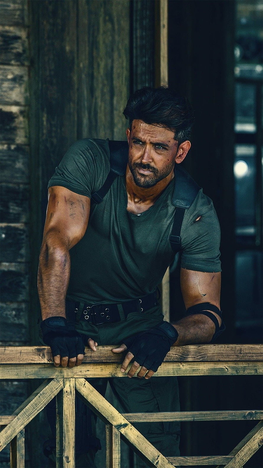 Hrithik Roshan in gritty military action pose leaning on wooden railing HD phone wallpaper