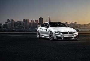 White BMW M4 F82 Sedan Parked on Asphalt with City Skyline at Dusk HD wallpaper