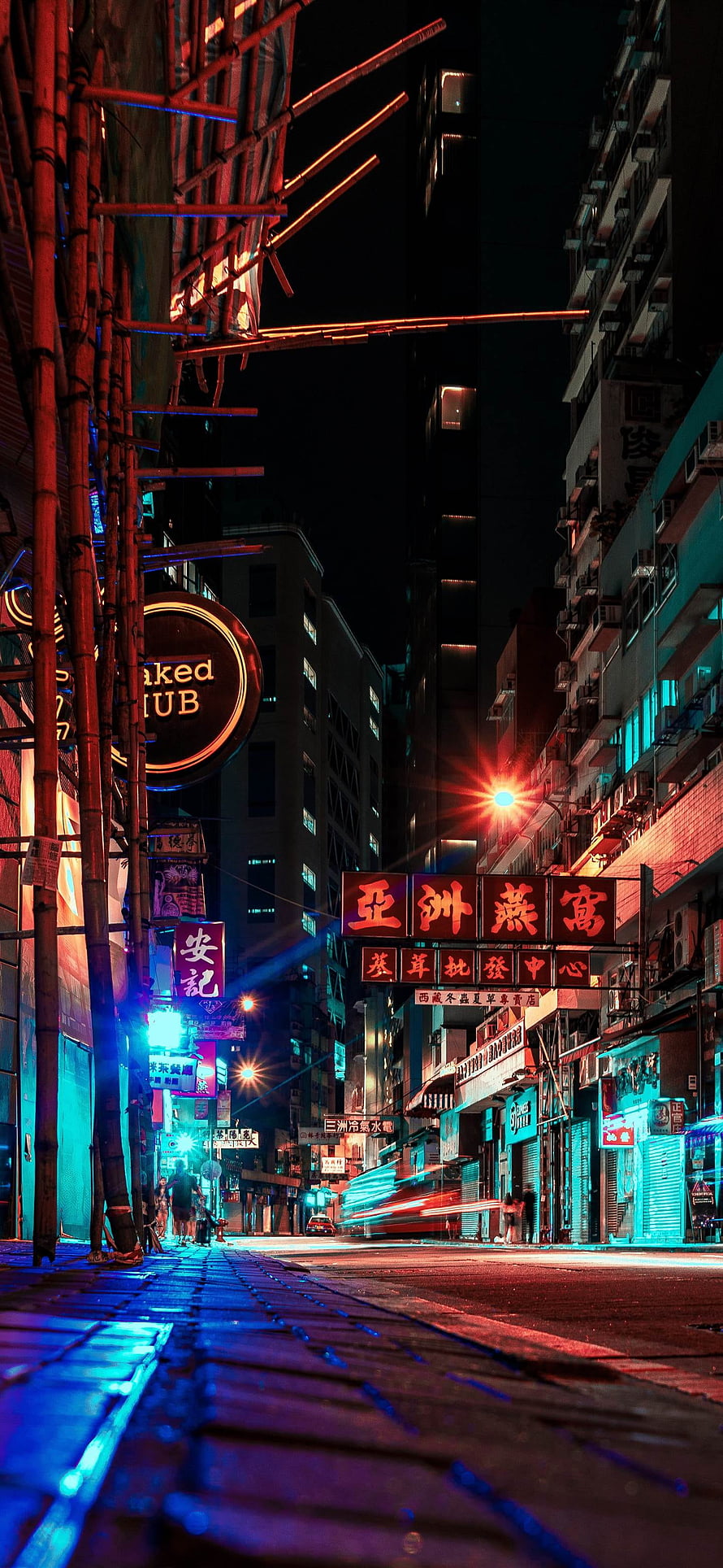 Neon-lit Hong Kong street at night with glowing signs and bamboo scaffolding HD phone wallpaper