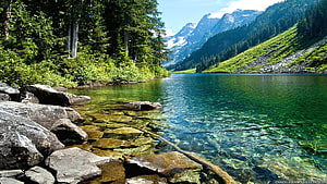 Crystal Clear Alpine Lake with Rocky Shore and Snow-Capped Mountains HD wallpaper