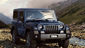 Mahindra Thar SUV parked on rocky riverbed with misty mountain backdrop HD wallpaper