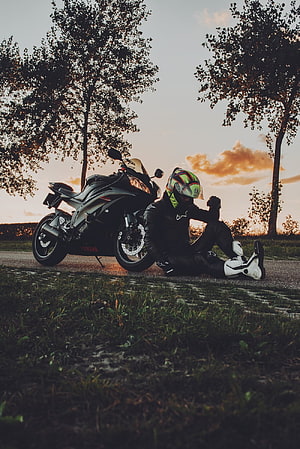 Biker Resting Beside Yamaha Motorcycle at Sunset in Scenic Countryside HD phone wallpaper