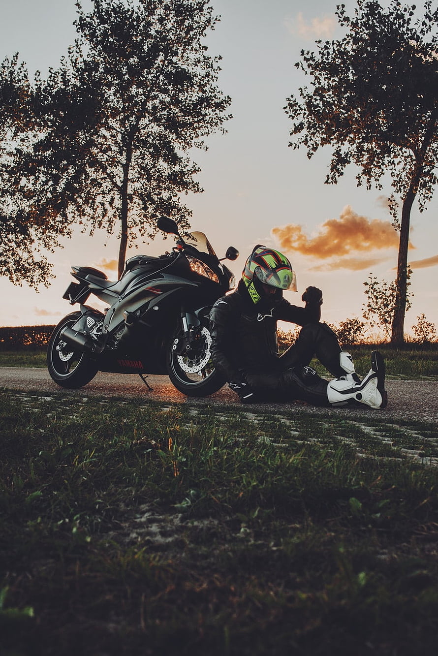 Biker Resting Beside Yamaha Motorcycle at Sunset in Scenic Countryside HD phone wallpaper