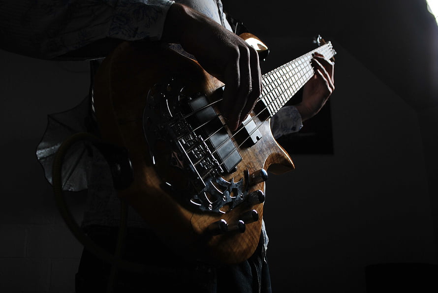 Close-up of a musician playing a wooden bass guitar in dramatic low-key lighting HD wallpaper