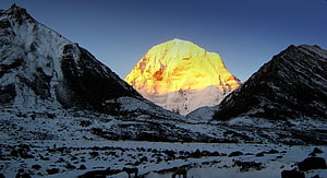 Mount Kailash glowing golden at sunrise above a snow-covered Himalayan valley HD wallpaper