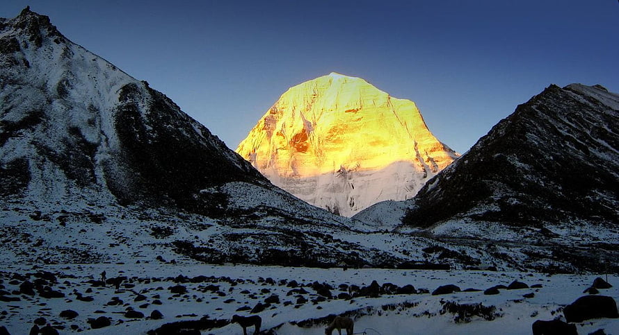 Mount Kailash glowing golden at sunrise above a snow-covered Himalayan valley HD wallpaper
