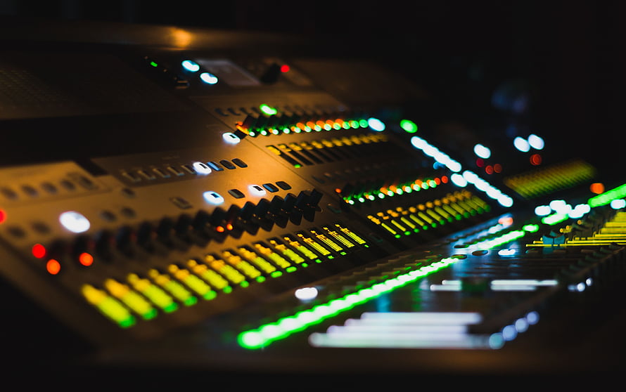 Professional Audio Mixing Console with Glowing Faders and Illuminated Level Meters in a Dark Studio HD wallpaper