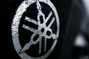 Close-up of a wet Yamaha emblem with water droplets on a dark background HD wallpaper