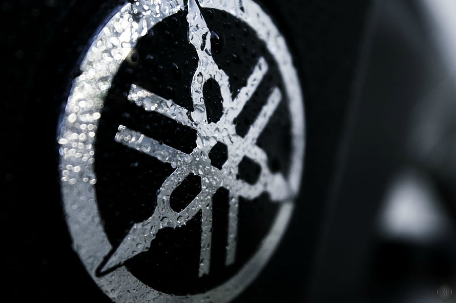 Close-up of a wet Yamaha emblem with water droplets on a dark background HD wallpaper