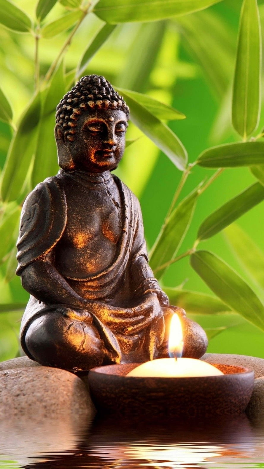 Serene Bronze Buddha Statue in Meditation with Candlelight and Bamboo Leaves HD phone wallpaper