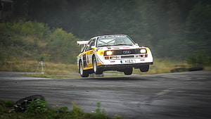 Audi Sport Quattro S1 E2 Rally Car Mid-Air Jump on Wet Forest Road HD wallpaper