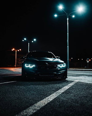 Matte Black BMW M4 Coupe Parked on Wet Asphalt Under Streetlights at Night HD phone wallpaper