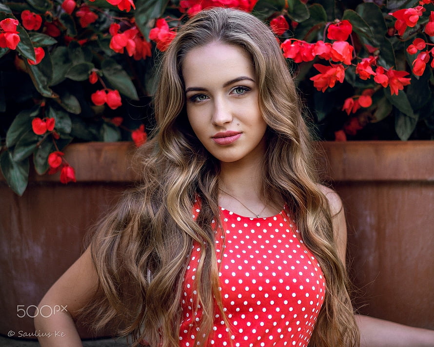 Young Woman in Red Polka Dot Top with Long Wavy Hair Against Red Flowers HD wallpaper