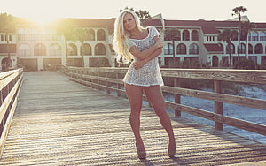 Blonde model in white lace dress posing on a coastal wooden boardwalk at golden hour HD wallpaper