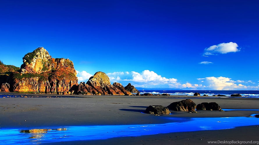 Coastal Rock Formations on a Sandy Beach Under a Deep Blue Sky HD wallpaper