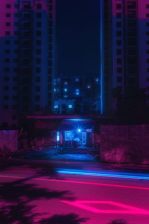 Neon-lit urban street at night with glowing storefront and long-exposure light trails HD phone wallpaper