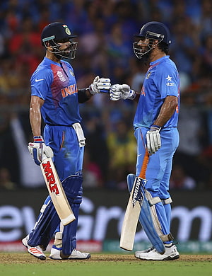 Virat Kohli and MS Dhoni in Indian cricket blue kits exchanging a handshake on the field HD phone wallpaper
