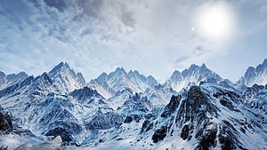 Majestic Snow-Capped Mountain Range Under a Bright Winter Sky HD wallpaper