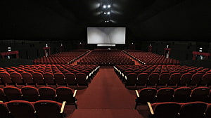 Empty Movie Theater Interior With Rows of Red Seats and Large Projection Screen HD wallpaper