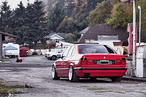 Rear Three-Quarter View of a Red BMW E34 532i Sedan with Custom White Wheels HD wallpaper