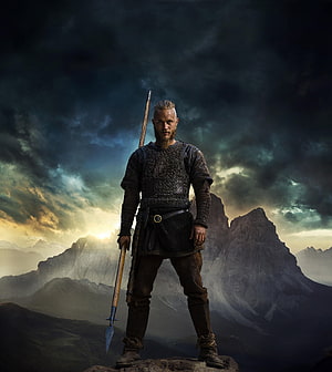 Ragnar Lothbrok from Vikings Standing on a Rocky Peak with a Spear Under a Dramatic Sky HD phone wallpaper