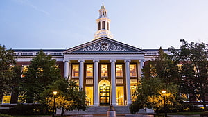Harvard Business School Main Building at Dusk with Illuminated Windows and Classical Columns HD wallpaper