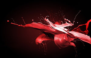 Dynamic red liquid splash frozen in motion against a dark background HD wallpaper