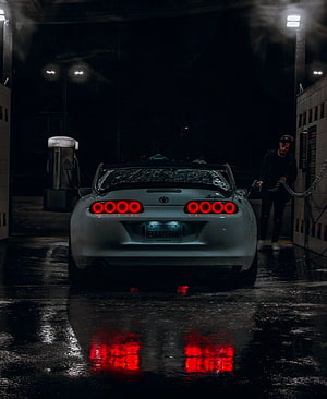 Rear View of a Silver Toyota Supra at a Nighttime Gas Station with Wet Pavement Reflections HD phone wallpaper